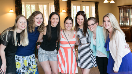 Seven young women looking forward with their arms around each other's waists