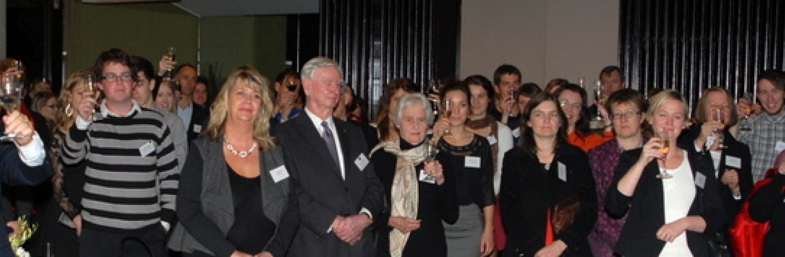 Large group of people raisign their glasses to toast