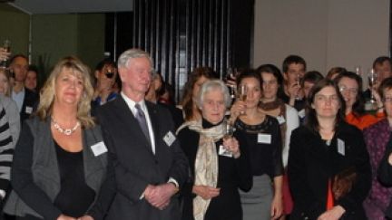 Large group of people raisign their glasses to toast