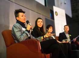 Four people sitting in chairs speaking into microphones. 