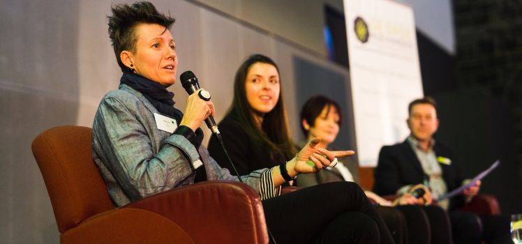 Four people sitting in chairs speaking into microphones. 