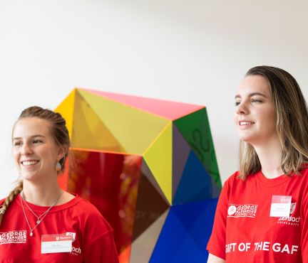 Two female Murdoch University students in red t-shirts with Gift of the GAF on them