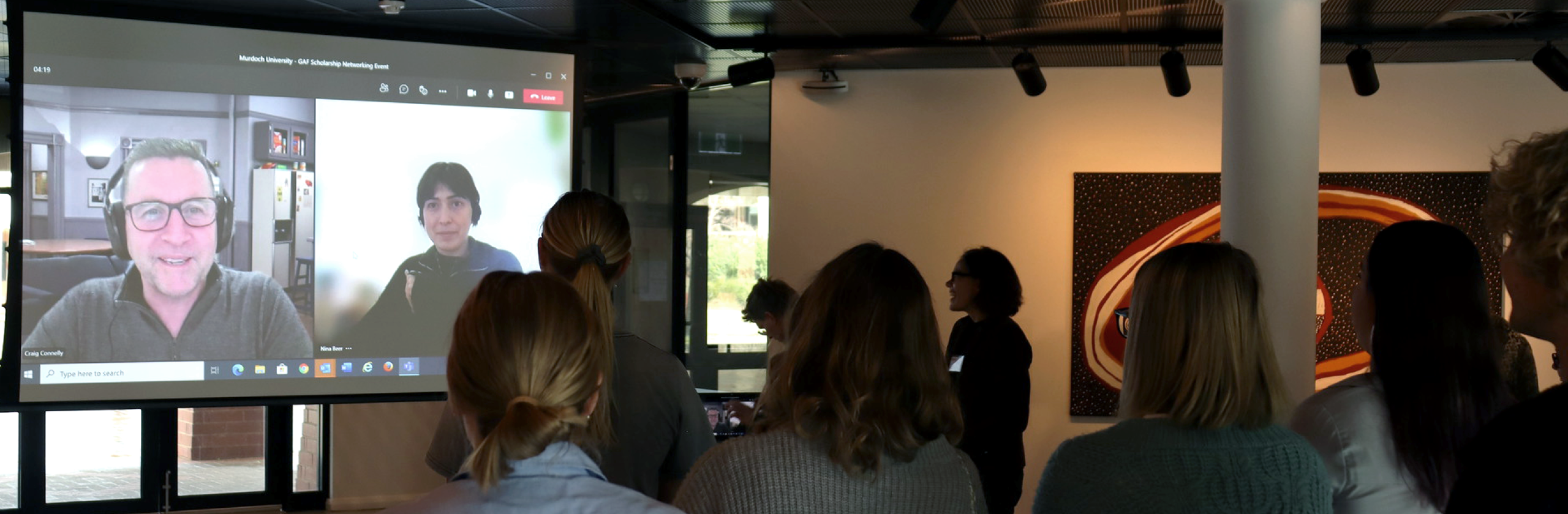 Students looking at a large screen showing GAF staff on Zoom