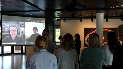 Students looking at a large screen showing GAF staff on Zoom