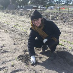 Anna, RMIT scholar, kneeling on ground outside
