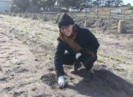 Anna, RMIT scholar, kneeling on ground outside