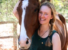 Josette Fretton, Murdoch University scholar. Young woman smiling with her arm wrapped around a brown and white horse.