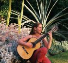 Paz Pisarski, RMIT University scholar. Woman in garden playing a guitar.