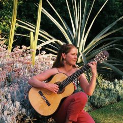 Paz Pisarski, RMIT University scholar. Woman in garden playing a guitar.