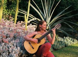 Paz Pisarski, RMIT University scholar. Woman in garden playing a guitar.
