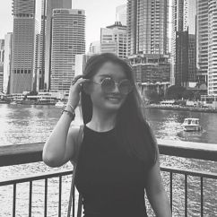 Serine Lee, Griffith University scholar. Black and white image of young woman smiling in front of a city scape. 