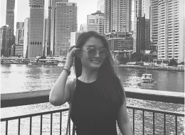 Serine Lee, Griffith University scholar. Black and white image of young woman smiling in front of a city scape. 