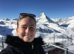 Simone De Nys, ANU scholar. Blonde woman with a black fluffy jacket standing in front of a snowy mountain range.