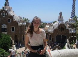 Yougn woman sitting on a low wall overlooking Gaudi buildings in Barcelona