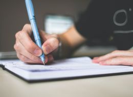 Up close view of a hand holding a pen and writing in a journal