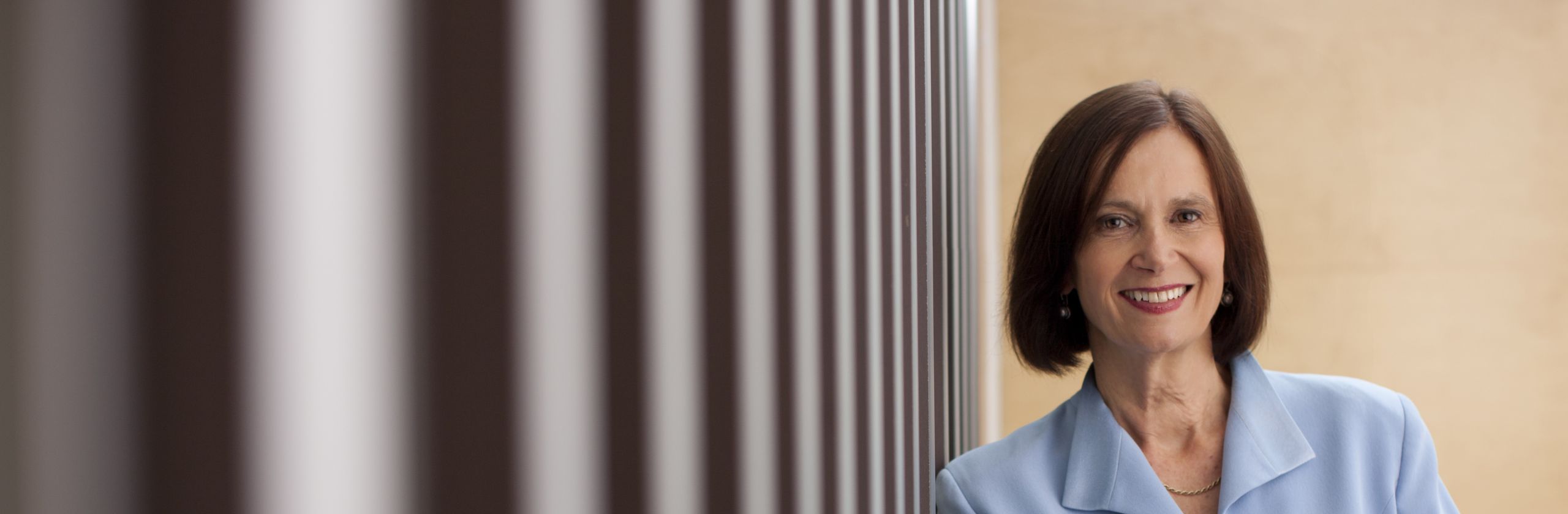 Woman in blazer leaning against wall