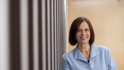 Woman in blazer leaning against wall