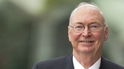 Headshot of elderly man in a suit smiling
