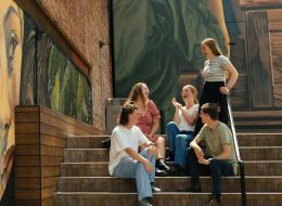 Group of students sitting and standing on stairs.