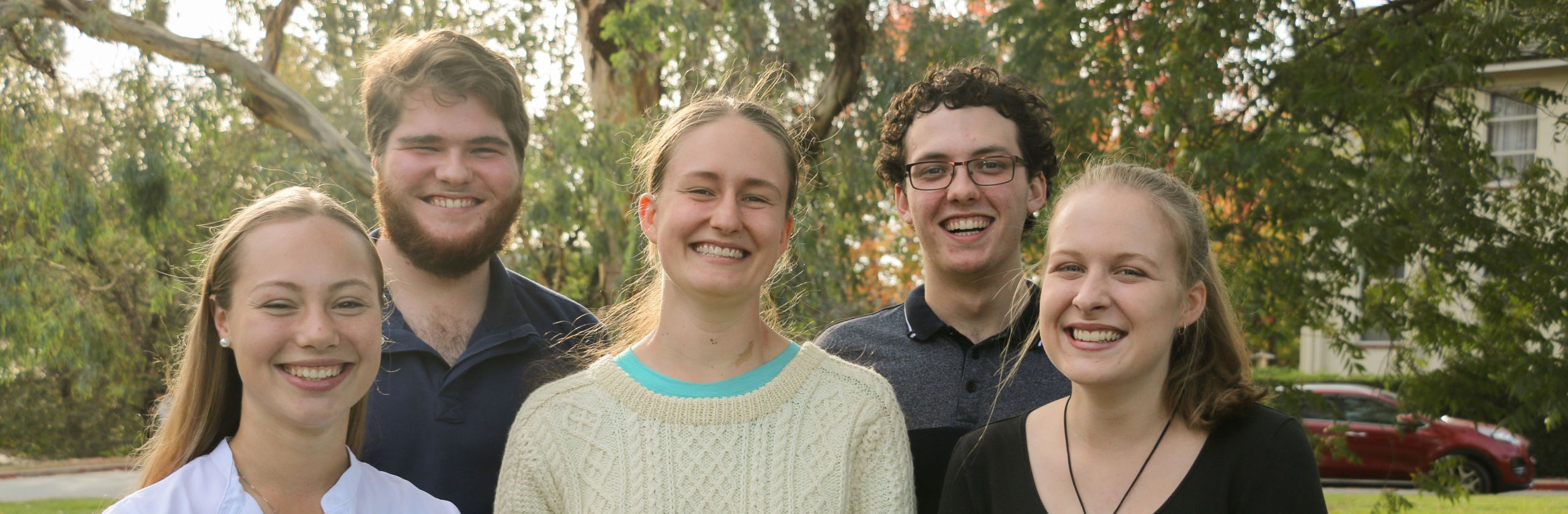A group of five ANU Scholars smiling and standing outside, on campus. 