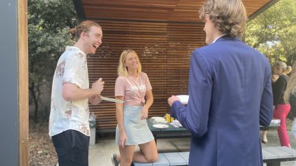 Three students stadnign around a picnic table and laughing