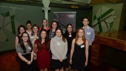 A group of mostly female students standing in front of a RMIT banner