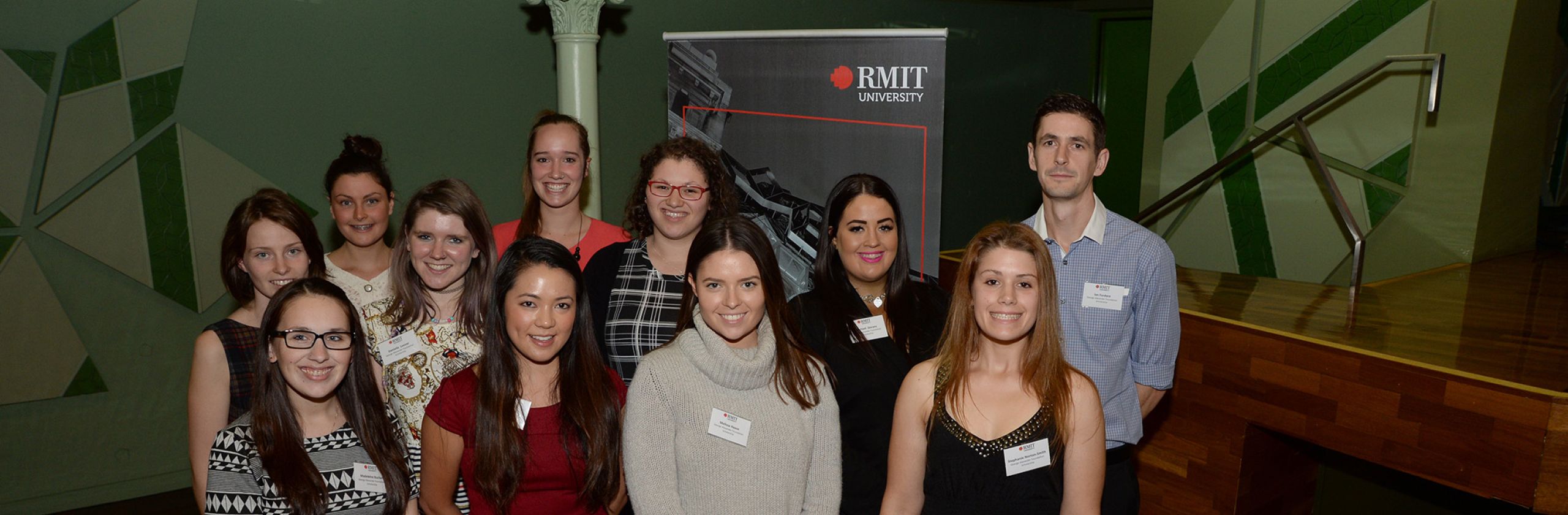 A group of mostly female students standing in front of a RMIT banner