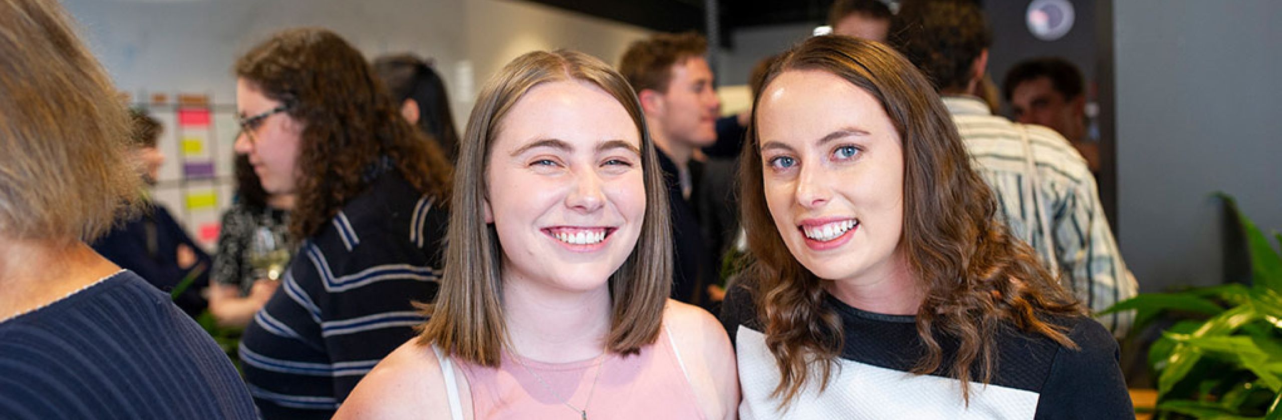 Two scholars smiling, other people standing in the background.