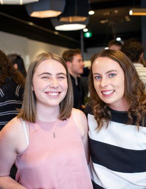 Two scholars smiling, other people standing in the background.