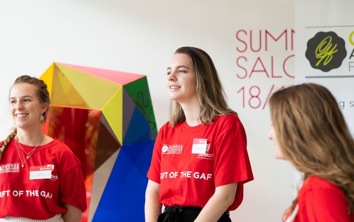 Two Murdoch University scholarship recipients wearing red t-shirts and smiling.