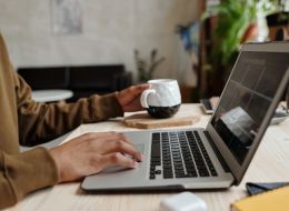 Student working on laptop with a mug in the foreground