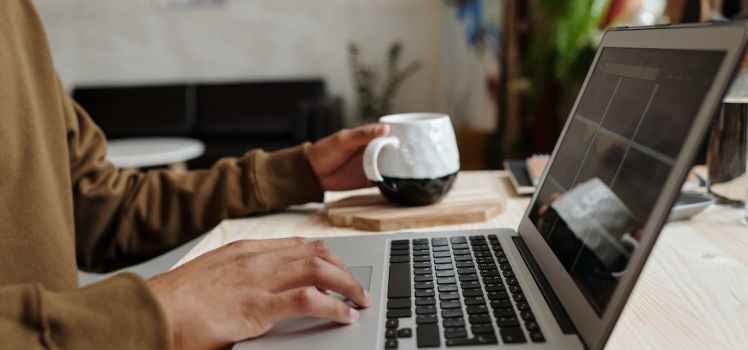 Student working on laptop with a mug in the foreground
