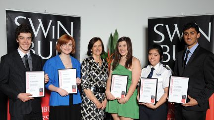 Five students holding their scholarship certificates in front of Swinburne banners