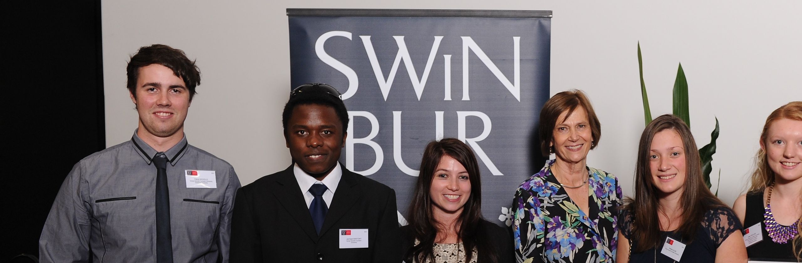 A group of yougn students standing in front of Swinburne sign