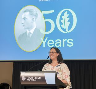 Woman on podium making speech at GAF 50th Anniversary Dinner.