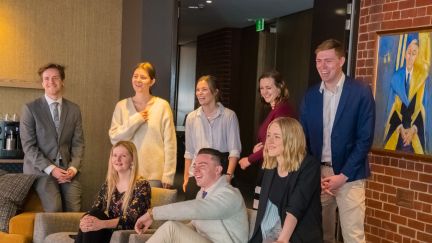 A group of 8 students sitting and standing smiling and laughing