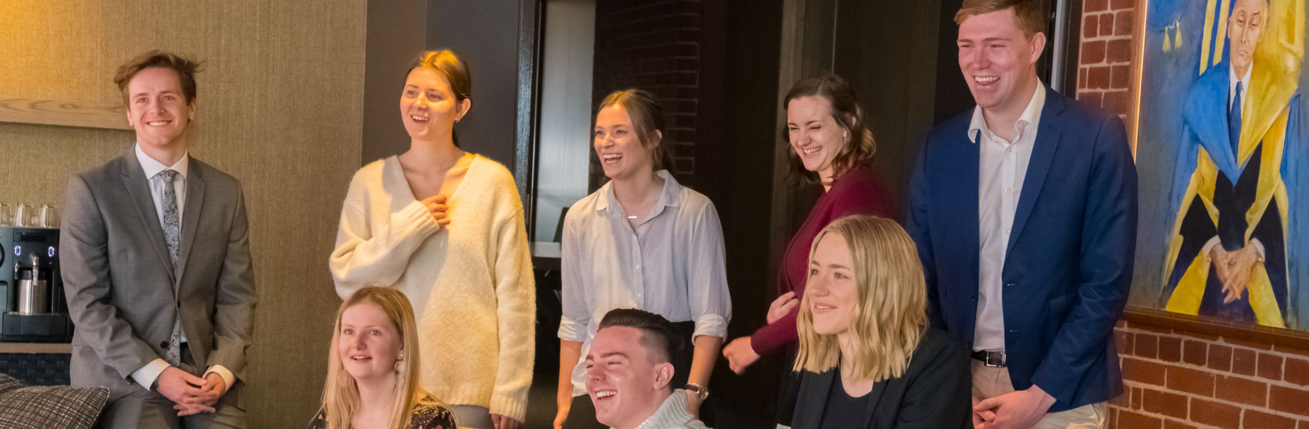 A group of 8 students sitting and standing smiling and laughing