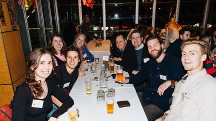 A group of male and female students sittiing around a table with drinks