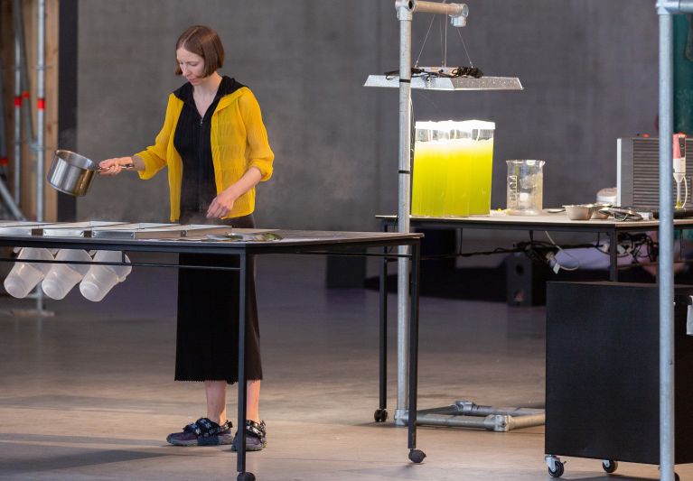 Woman in warehouse standing over bioplastic production line.