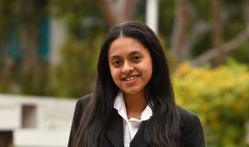 Young woman posing at photo in collared white shirt and black blazer.