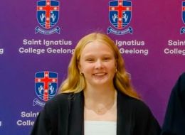 Woman smiling at camera standing in front of purple logo'd backdrop