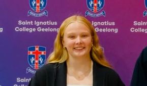 Woman smiling at camera standing in front of purple logo'd backdrop