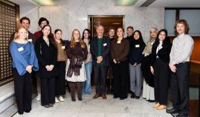 Line of people posing and smiling at camera on marble floor.